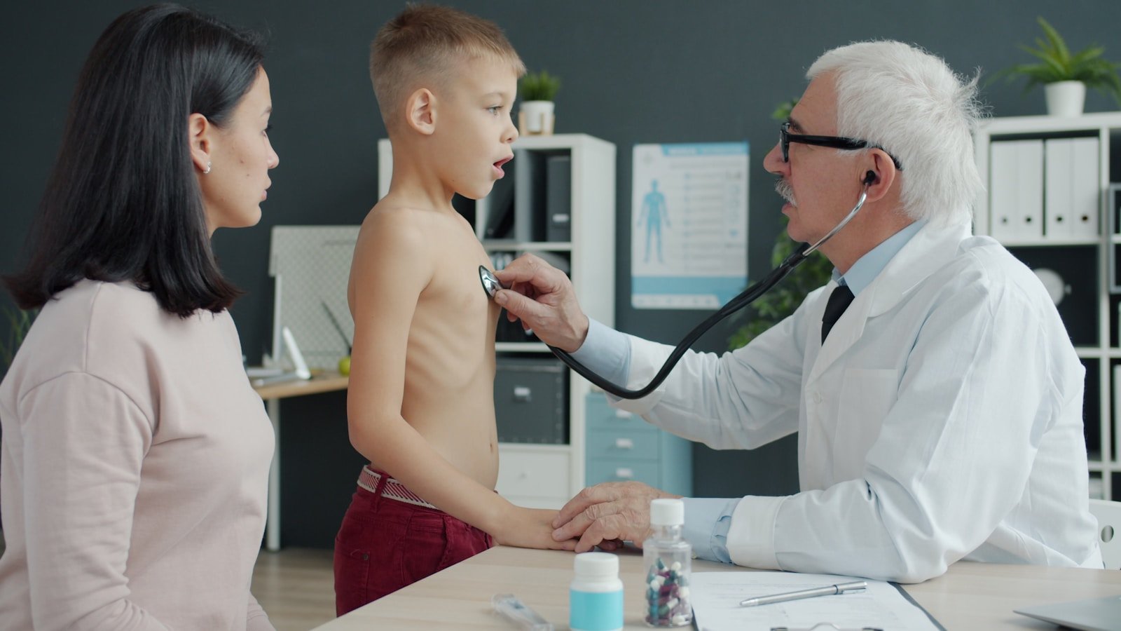 Doctor examines a young boy's chest with stethoscope.